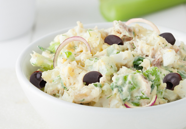 Mediterranean Potato Salad with kalamata olives and onions in a white bowl