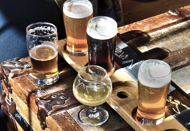 Flight of various beers on a raw wood bar top