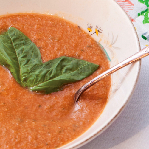 A bowl of chilled tomato soup with a fresh thyme leaf