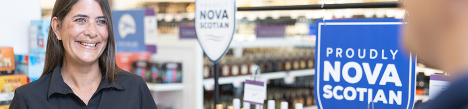 Smiling team member with store and proudly Nova Scotian shield in the background