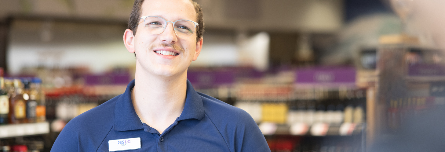 NSLC team member with glasses on, NSLC store in the background