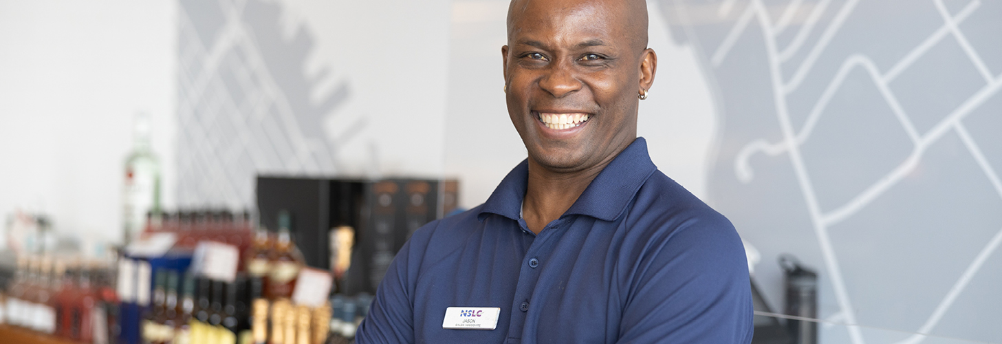 NSLC team member stands in front of a checkout with products in the background.