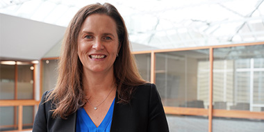 Tara wearing a black blazer and blue shirt smiling. 