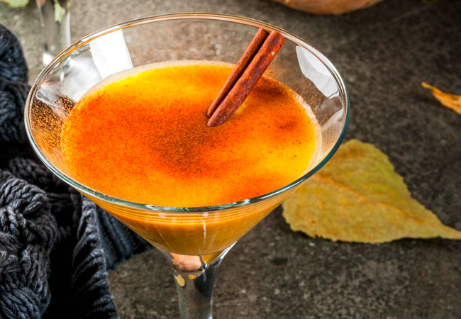 A mixed rum drink sprinkled with cinnamon and garnished with a cinnamon stick