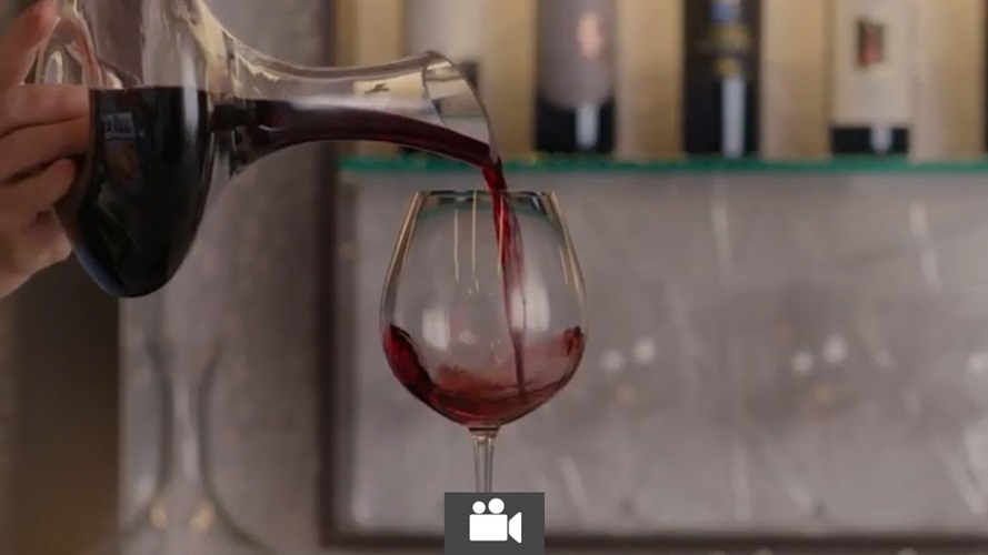 Wine being poured into a wine glass from a decanter.