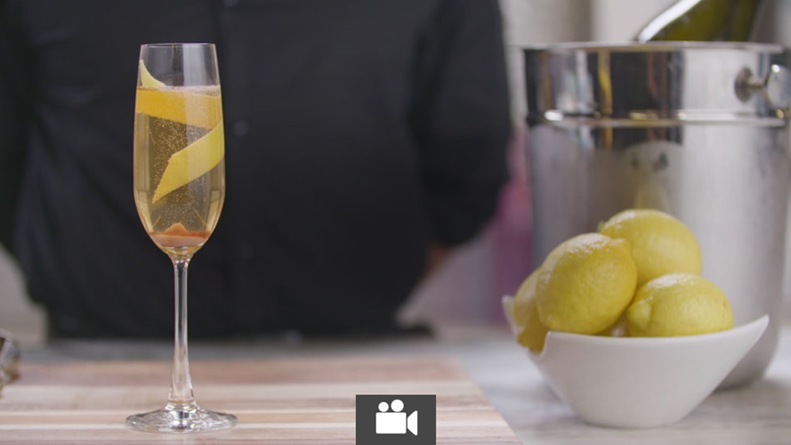 A champagne glass with a mixed drink garnished with a lemon twist.