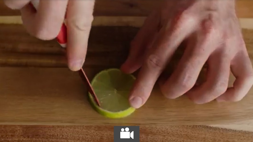 Someone cutting the skin off a lime slice.