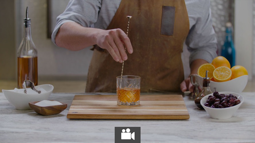 A bartender mixing a drink with a bar spoon.