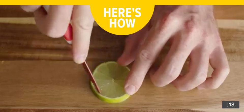 Someone cutting a lime on a wooden cutting board with the words "Here's How".