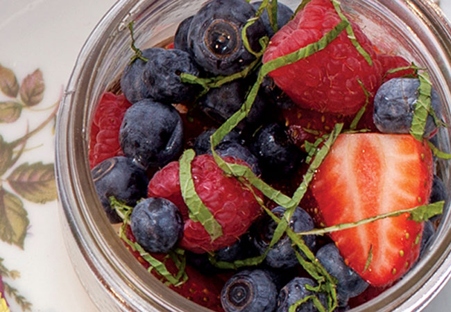 Overhead shot of mixed berries in a mason jar with chopped mint garnish