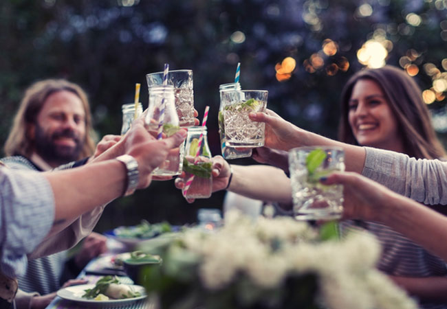 People smiling around a dinner table, cheers simple cocktails