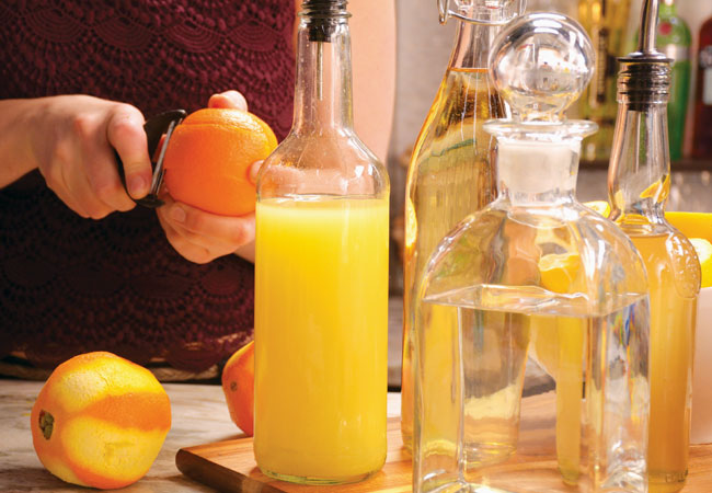 Bartender peeling oranges for drink with orange rinds.