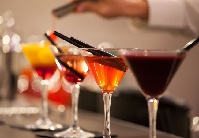 Four colourful craft cocktails in martini glasses