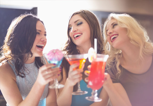 Three young smiling women with stylish cocktails 
