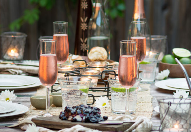 Artfully arranged dining table with tall wine glasses of rose sparkling wine