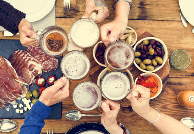 Overhead image of people toasting with assorted ciders, charcuterie boards arrange on the table