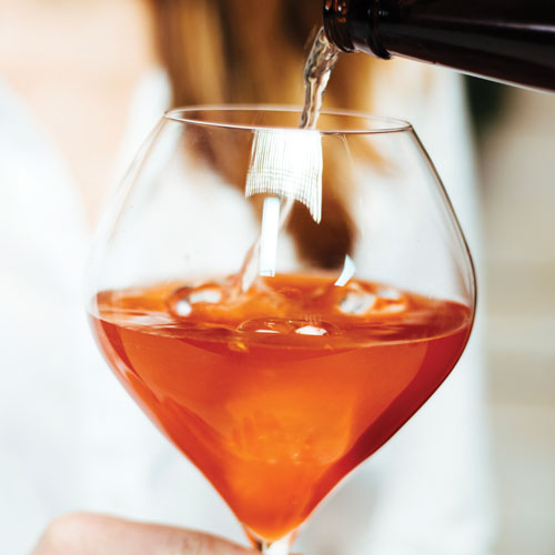 Rum being poured from the bottle into a wine glass filled with ginger beer