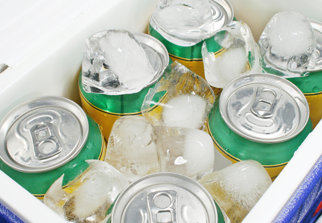 Beer cans in a blue cooler filled with ice cubes
