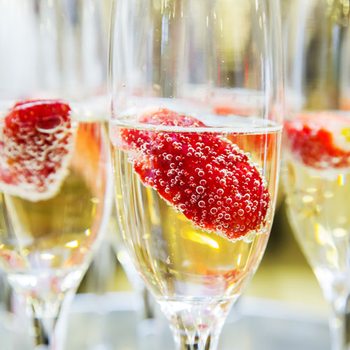  A field of champagne flutes with raspberries