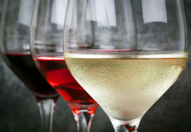 A glass of white, red and rosé wine against a tile background