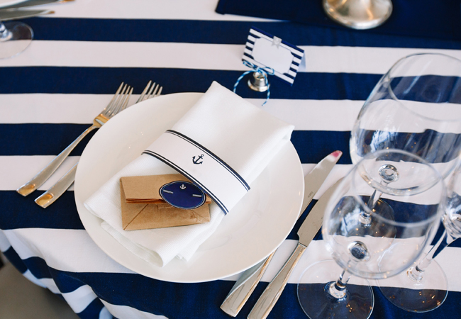 Overhead view of a nautical themed place setting on a blue and white table cloth