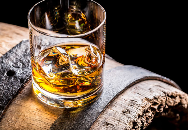A scotch on the rocks sitting on a barrel