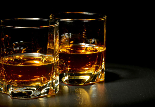 two glasses of scotch with a black background