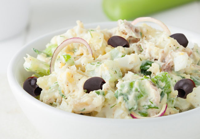 Mediterranean Potato Salad with kalamata olives and onions in a white bowl