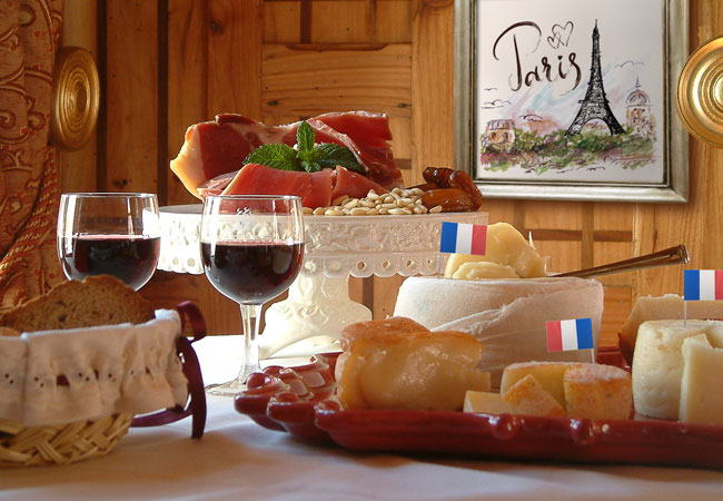 Charcuterie place setting with two glasses of wine and French flag in the wheels of cheese