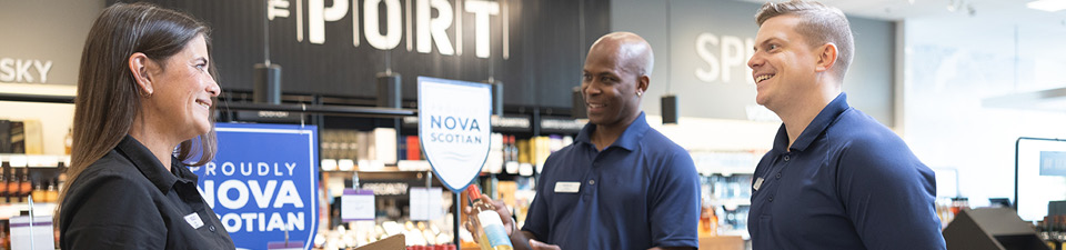 Three NSLC team members standing in a NSLC store. One is holding a clip board.