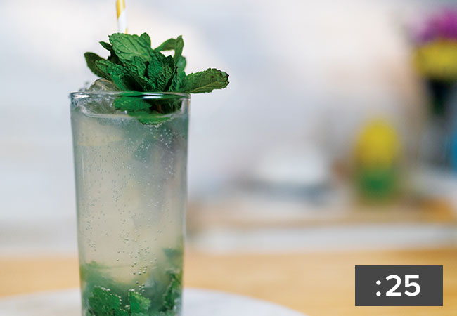 A closeup of a mixed drink in a highball glass, garnished with mint on top and crushed mint inside. Recipe video is 25 seconds.