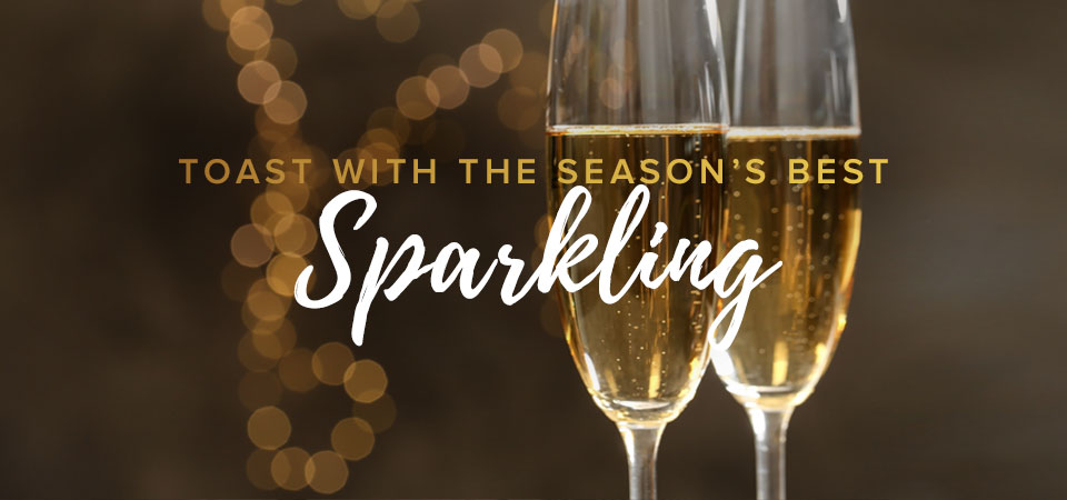 Two champagne glasses of sparkling wine with a light bokeh background. Text that says “Toast with the Season’s Best Sparkling”.