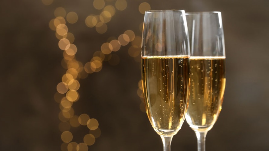 Two champagne glasses of sparkling wine with a light bokeh background.