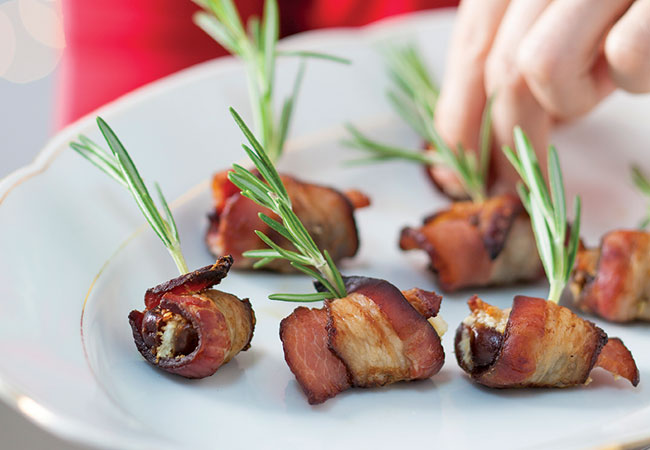 Bacon wrapped dates with a sprig of rosemary