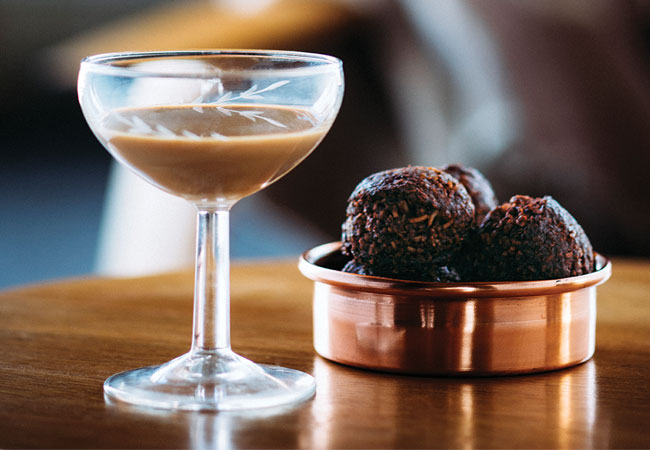 Creamy cocktail with chocolate macaroons in a copper dish. 