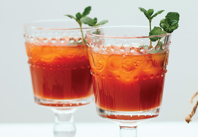 Two goblets of deep red Caesars with mint garnish. 