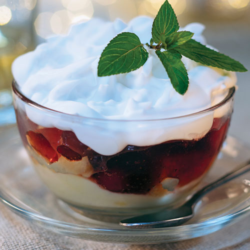 Cranberries and apples in a bowl topped with custard and whipped cream