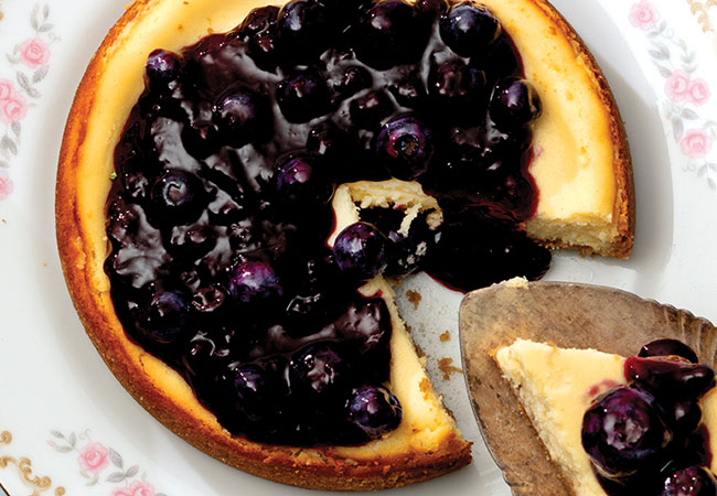 A golden cheesecake topped with blueberry sauce