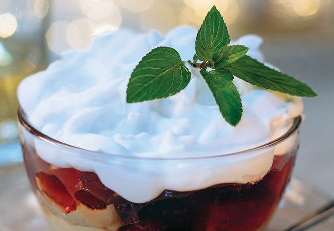 Cranberries and apples in a bowl topped with custard and whipped cream
