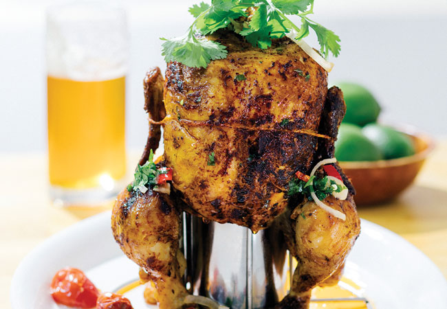 A whole chicken sitting on a beer can