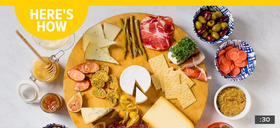 A charcuterie board filled with cheese, cured meats, olives, and spreads. Text reads, 'heres how' and includes a time stamp of 30 seconds in the corner.