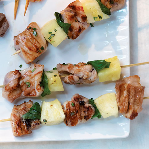 Three grill-marked chicken pineapple skewers on a plate.