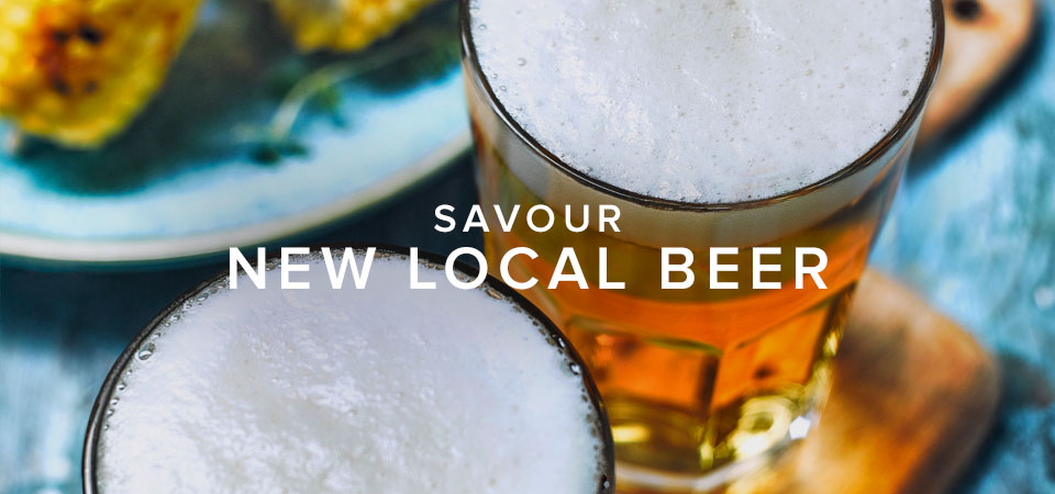 An aerial shot of two foamy beers with the words, 'Savour New Local Beer'.