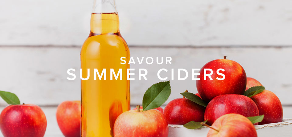 A beer bottle filled with golden-coloured cider and surrounded by apples. Includes text that reads, 'Savour Summer Ciders'.