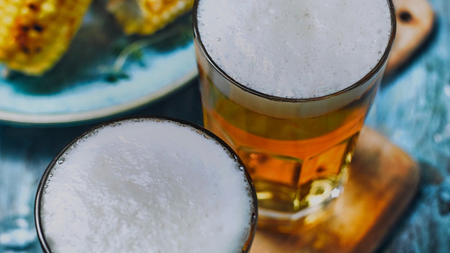 Two glasses of foamy beer.
