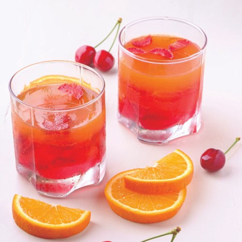 A cocktail glass filled with red liquid and an orange slice garnish.