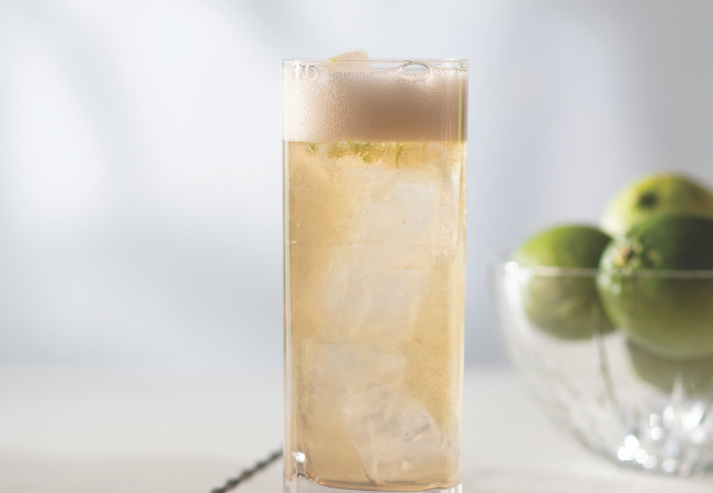 A glass filed with a caramel coloured liquid with foam. 