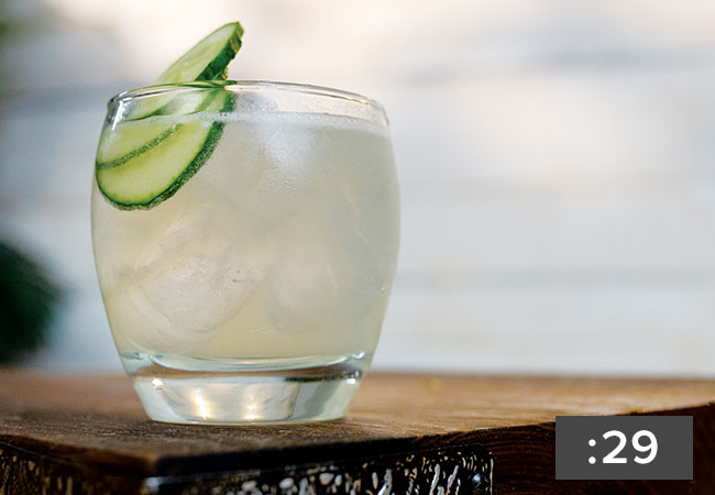 A clear liquid garnished with a cucumber.