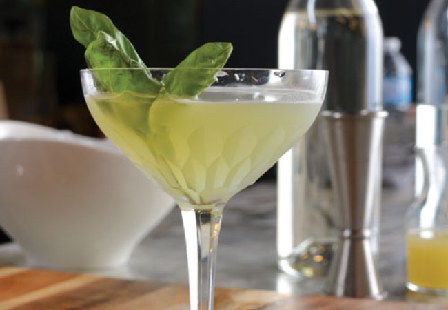 A green cocktail garnished with a mint sprig.