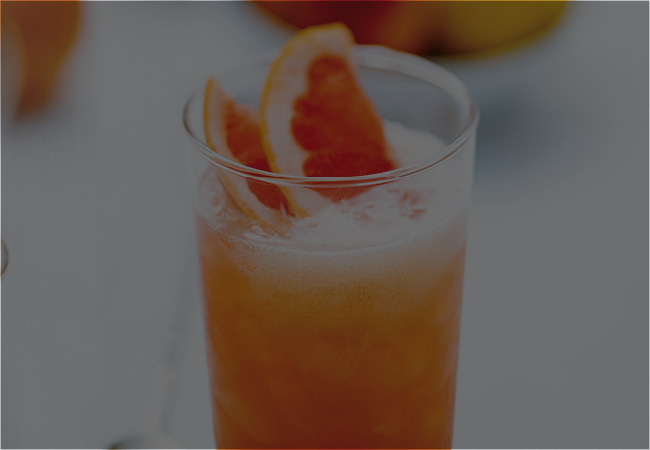 Glass with orange liquid and grapefruit wedges for garnish